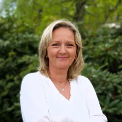 En mann som smiler foran en busk